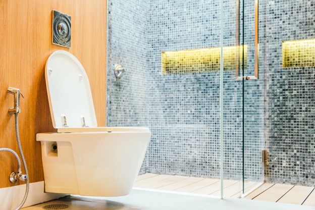 Modern wall-hung toilet bowl in a tiled bathroom with glass shower, showcasing Sims Lighting Gallery design inspiration for toilet bowl Singapore